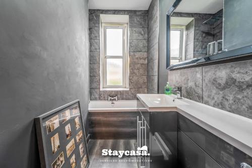 uma casa de banho com um lavatório e uma banheira em Stunning 3 Bdr Apartment 5 Min From Haymarket em Edimburgo