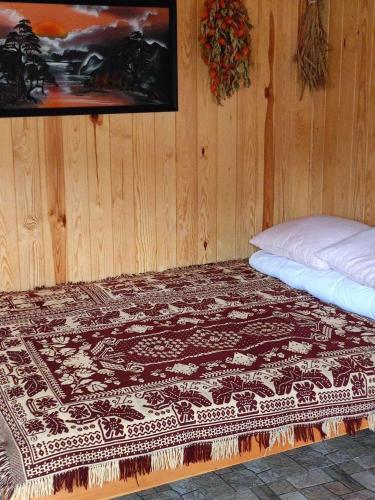 a bed in a wooden room with a blanket on it at DOMEK LETNISKOWY PRZY GÓRACH MAJOWYCH in Goniadz