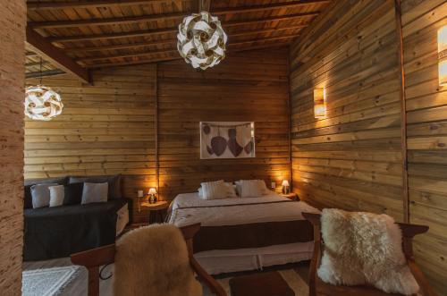 a log cabin bedroom with a bed and two chairs at Pousada Canto da Nascente in Monte Verde