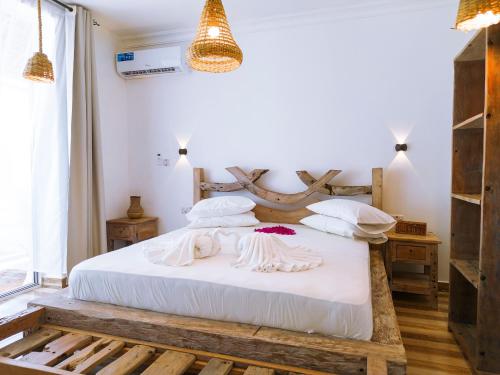 a bedroom with a white bed with a wooden headboard at Limiria Villa Zanzibar in Nungwi