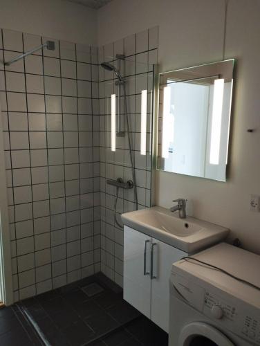 a bathroom with a sink and a shower with a mirror at (id024) Østergade 87. 1 tv in Esbjerg