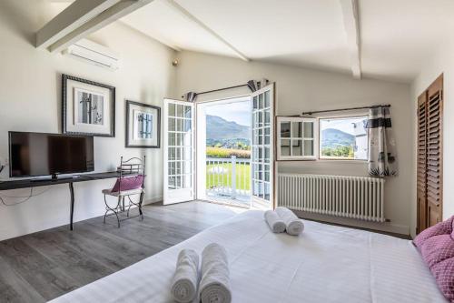 Schlafzimmer mit einem Bett, einem Schreibtisch und einem TV in der Unterkunft Magnifique Villa face à la Rhune in Ascain