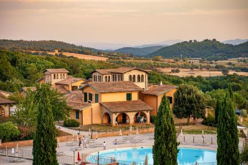 a villa with a swimming pool in front of a building at Pian Dei Mucini Resort in Massa Marittima