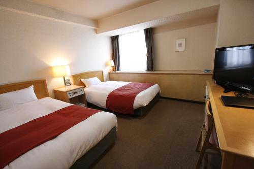 a hotel room with two beds and a flat screen tv at Hotel Abest Meguro in Tokyo