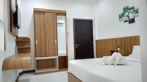 a bedroom with a white bed and a mirror at Hotel Bhakti Syariah in Padang