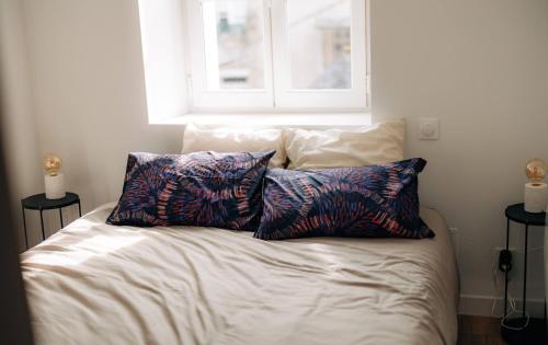 a bed with two pillows on it with a window at Les Balcons de Kéréon in Quimper