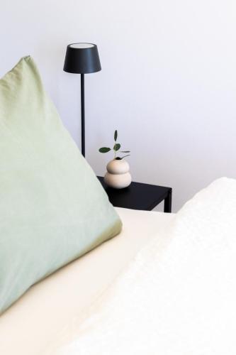 uma cama branca com uma almofada verde e um candeeiro em Elmi 33 em Wals