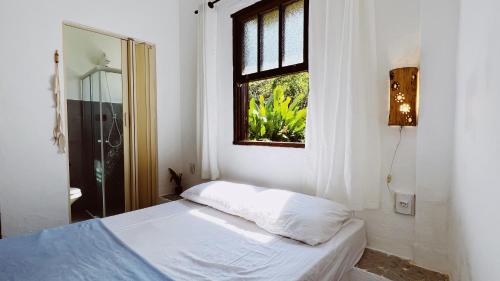 um quarto branco com uma cama e uma janela em Recanto da Floresta Suites em Ubatuba