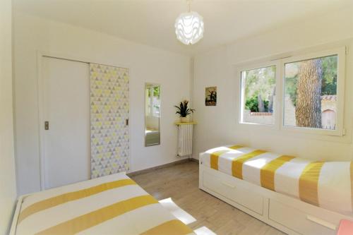 1 dormitorio con 2 camas y ventana en La Cigale Sanaryenne classé 4 étoiles face à un jardin méditerraneen, en Sanary-sur-Mer