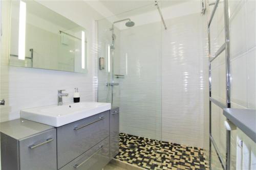 een witte badkamer met een wastafel en een douche bij La Cigale Sanaryenne classé 4 étoiles face à un jardin méditerraneen in Sanary-sur-Mer