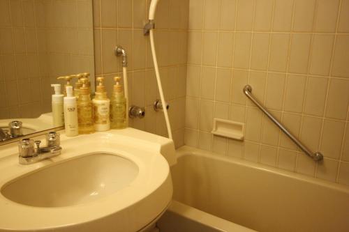 a bathroom with a toilet and a sink and a tub at Hotel Abest Meguro in Tokyo