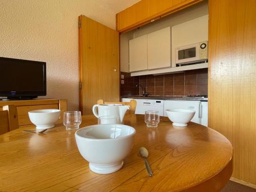 - une cuisine avec une table en bois avec des bols et des verres dans l'établissement Studio 4 pers. au pied des pistes à Méribel avec balcon et animaux acceptés - FR-1-411-397, à Les Allues