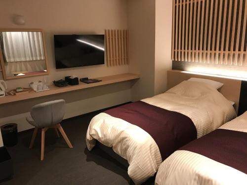 una camera d'albergo con due letti e una televisione di Aizu Tsuruya Hotel - Vacation STAY 57216v ad Aizuwakamatsu