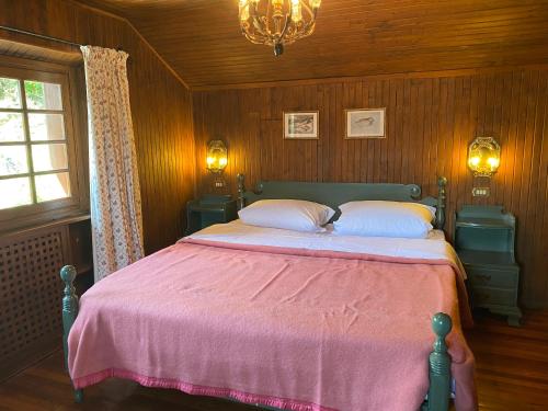 ein Schlafzimmer mit einem großen Bett mit einer rosa Decke in der Unterkunft Chalet Miralago in Plesio