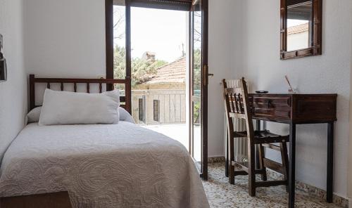 a bedroom with a bed and a desk and a window at Hostal Desde 1972 Yusta in Colmenarejo