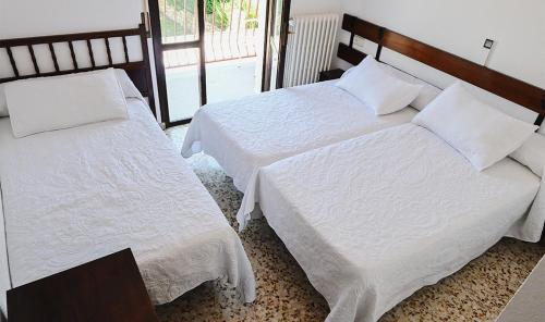 two beds in a hotel room with white sheets at Hostal Desde 1972 Yusta in Colmenarejo