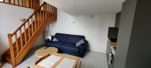 - un salon avec un canapé bleu et une table dans l'établissement Joli studio vue mer, à Menton