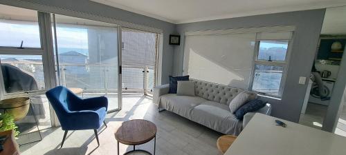 een woonkamer met een bank en een tafel bij 201 Coral Island, 88 Coral Road, Bloubergstrand in Bloubergstrand