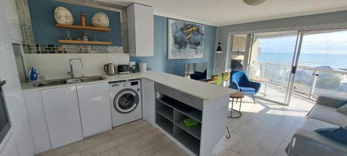 a kitchen with a sink and a washing machine at 201 Coral Island, 88 Coral Road, Bloubergstrand in Bloubergstrand