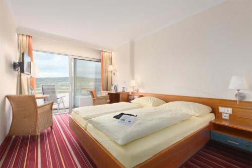 Habitación de hotel con cama y balcón en Trip Inn Landhotel Badsoden-Salmünster, en Bad Soden-Salmunster