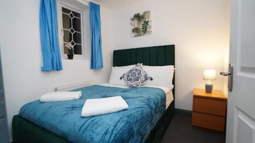 um quarto com uma cama azul e 2 almofadas em E2M Stays 3Bed Spacious House Free Parking Close To Heathrow em Farnham Royal