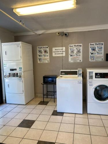 a laundry room with white appliances and signs on the wall at Motel 6-Lantana West Palm Beach, FL in Lantana
