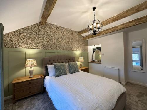 a bedroom with a large bed and a chandelier at Lavender Cottage with a hot tub in Deganwy