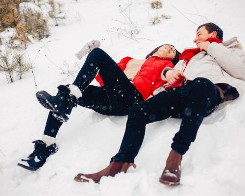 a man and a woman laying in the snow at Residence Nube D'Argento in Sestriere