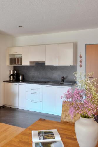 a kitchen with white cabinets and a vase with flowers at Hölderle Damüls in Damuls