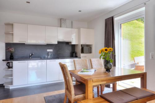 a kitchen with white cabinets and a wooden table at Hölderle Damüls in Damuls