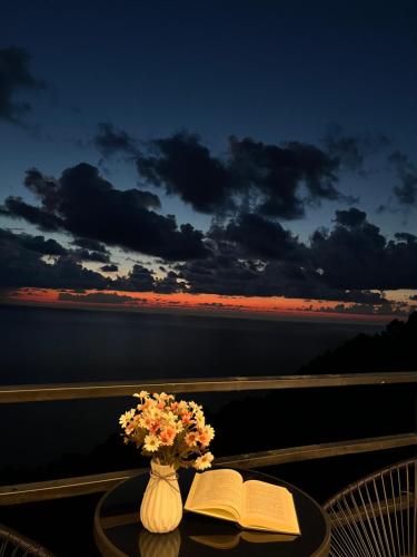 a table with a book and a vase with flowers on it at Panorama Sarpi in Batumi