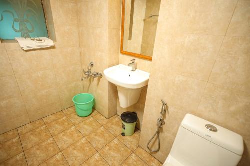 a bathroom with a sink and a toilet and a mirror at Liwa Tower Hotel & Business Center in Kunnamkulam
