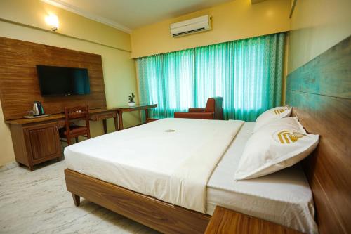a hotel room with a large bed and a desk at Liwa Tower Hotel & Business Center in Kunnamkulam