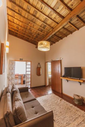a living room with a couch and a tv at Pousada Canto da Nascente in Monte Verde