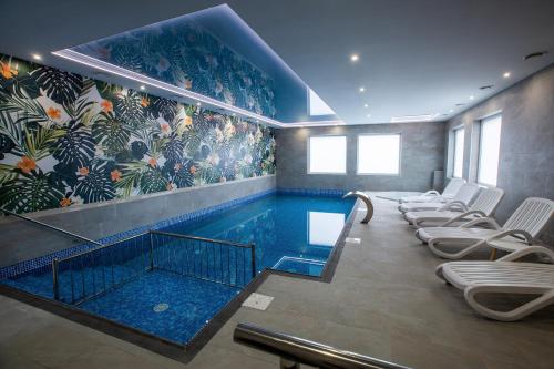 a swimming pool with chairs in a room with a mural at Jurajski Kryształ in Zaborze