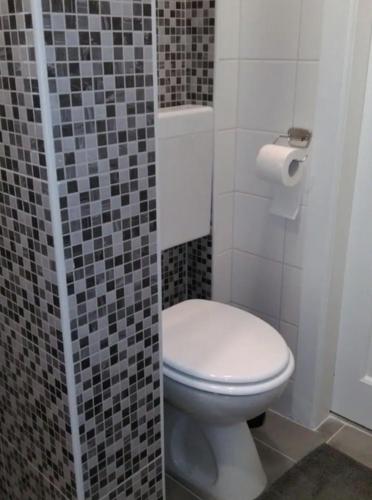 a bathroom with a toilet and a tiled wall at Habitat in Senaki