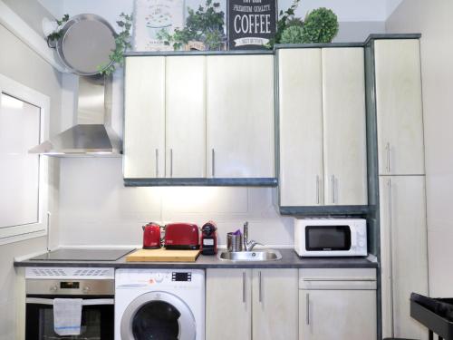 a kitchen with white cabinets and a washing machine at Paz y calma en Madrid centro in Madrid