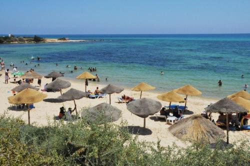 a group of people on a beach with umbrellas at Hôtel Romane in Hammamet