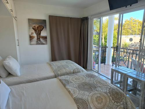 a bedroom with a bed and a balcony at Come Home in Oudtshoorn Self-Catering Units in Oudtshoorn