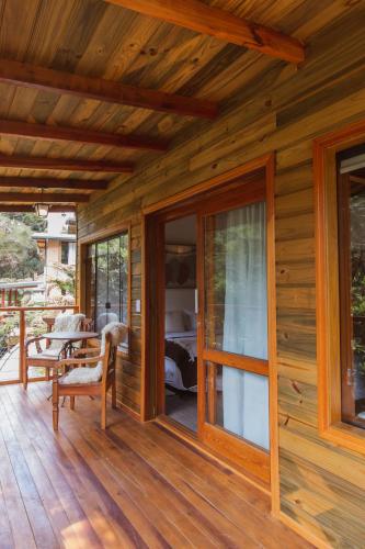 a wooden house with a deck with a bedroom at Pousada Canto da Nascente in Monte Verde