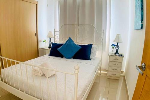 a white bed with blue pillows in a bedroom at Boca del Mar, Torre II, Apto. 402 in Cuevas