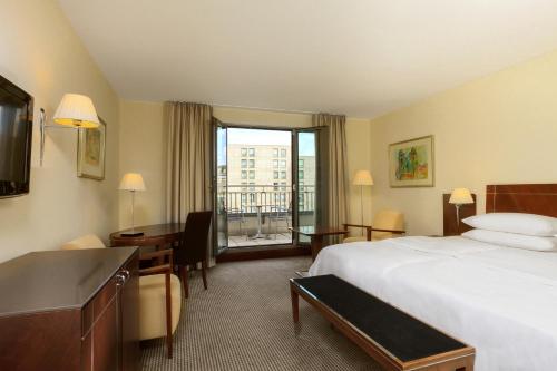 ニュルンベルクにあるシェラトン カールトン ニュルンベルクのベッドとデスクが備わるホテルルームです。