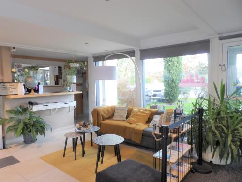 a living room with a couch and some plants at Logis Hotel Restaurant Le Jardin Délice in Saint-Victor