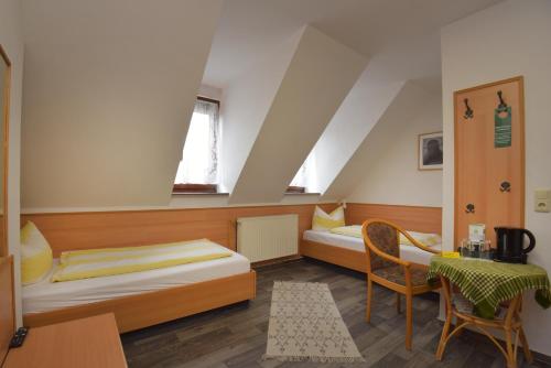 a bedroom with two beds and a table and a chair at Pension Bergstube in Bad Langensalza