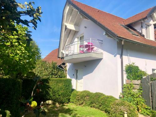 ein weißes Haus mit einem Balkon mit rosa Stühlen darauf in der Unterkunft Maison de campagne en Alsace 