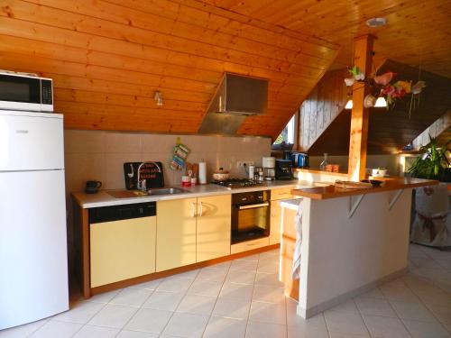 a kitchen with white appliances and a wooden ceiling at Maison de campagne en Alsace 
