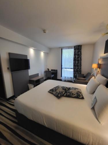 Pokój hotelowy z dużym łóżkiem i telewizorem w obiekcie Kyriad Saint Quentin en Yvelines - Montigny w mieście Montigny-le-Bretonneux