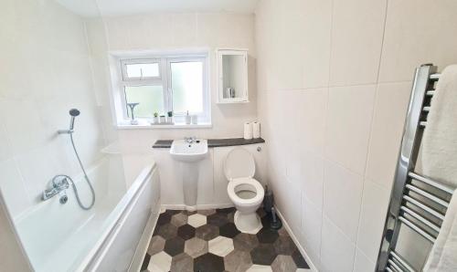 a white bathroom with a toilet and a sink at 2 Bed Spacious Apartment, Sleeps 5, Free Wifi, Free Parking, Amenities Nearby, Good Transport Links Nearby, Contractors and Holidays in Harlow