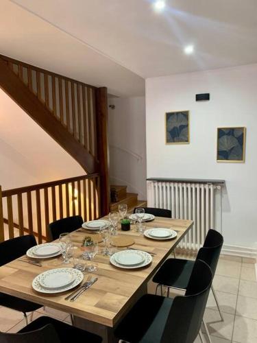 - une table en bois avec des chaises, des assiettes et des verres à vin dans l'établissement Maison Okaina, Sauna, Au centre-ville de Macon, à Mâcon