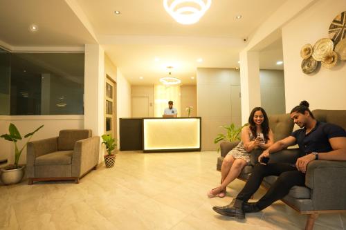 a man and a woman sitting on chairs in a lobby at Coastal Pearl Hotel Margao Railway Station in Madgaon
